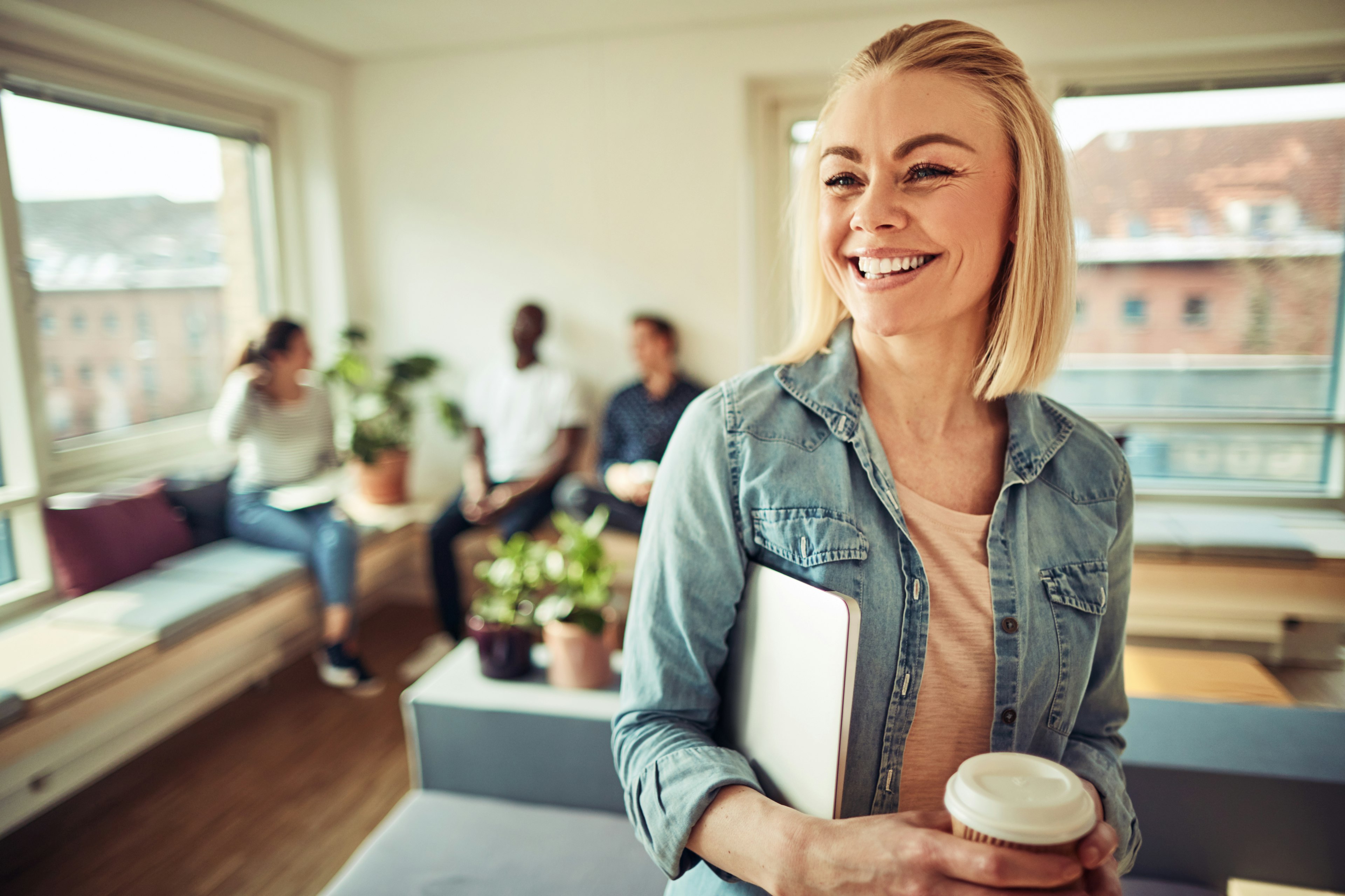 Leende kvinna som håller i en kaffekopp och ett block 