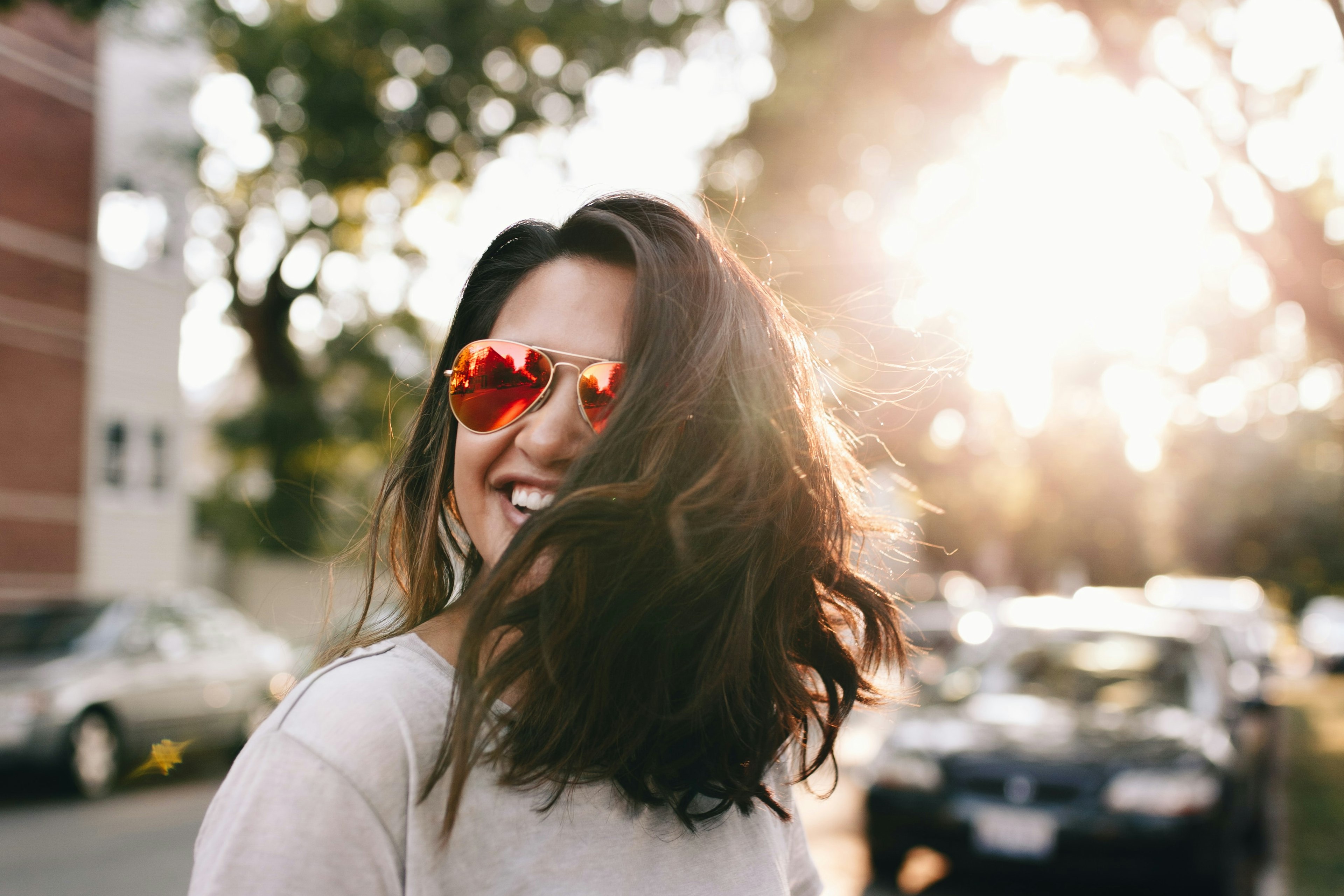 Glad kvinna med röda solglasögon är ute i solen