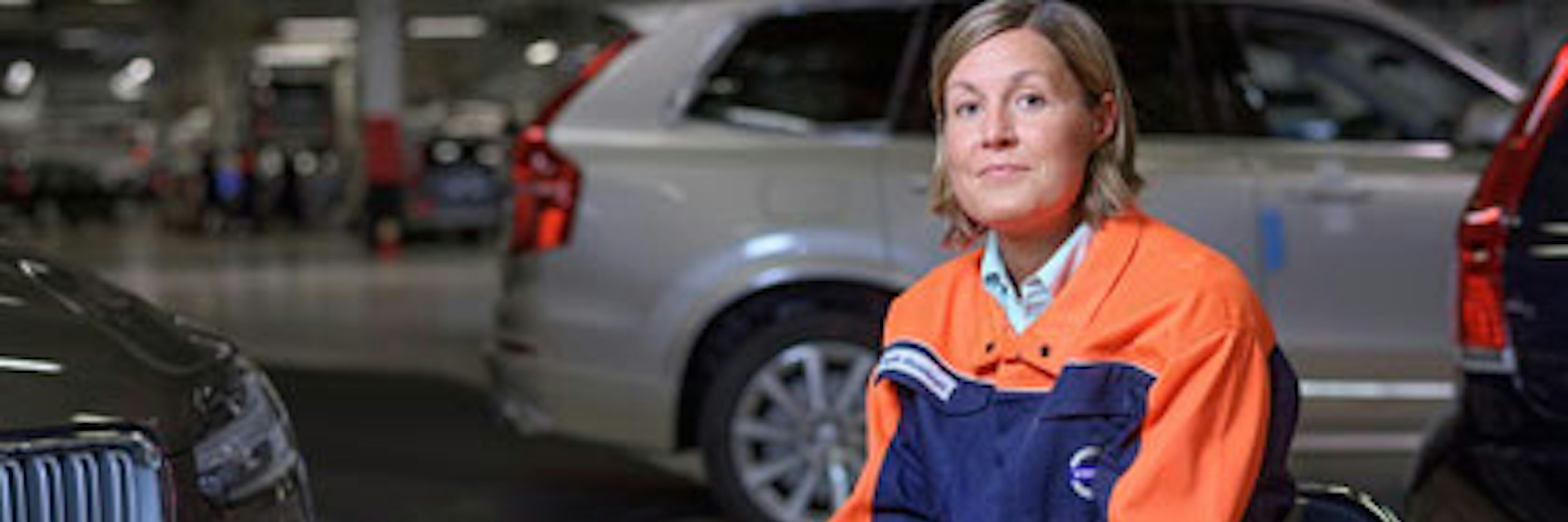 En kvinnlig anställd på Volvo sitter på en stol i en lokal med bilar