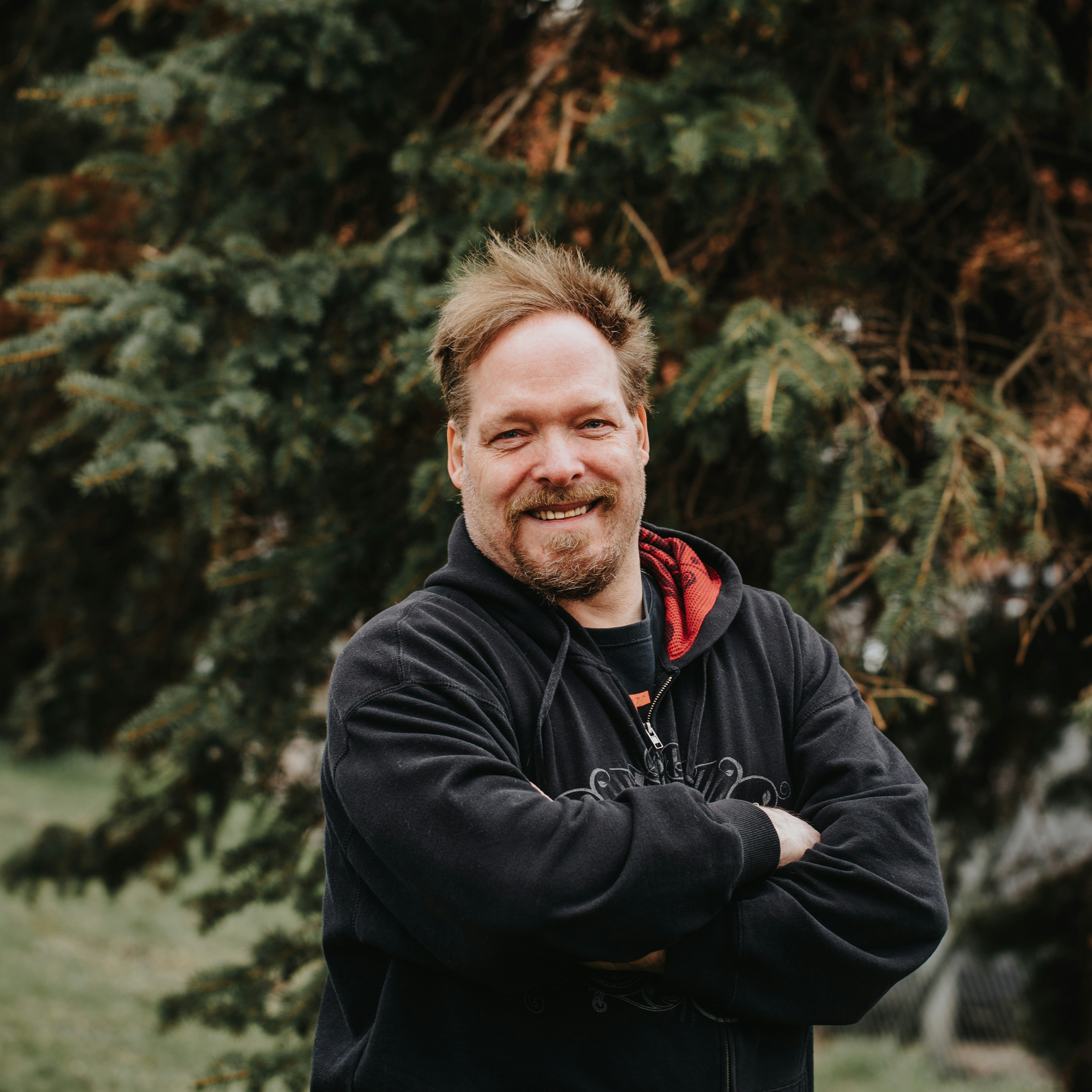 Porträtt på en man med en stor gran i bakgrunden