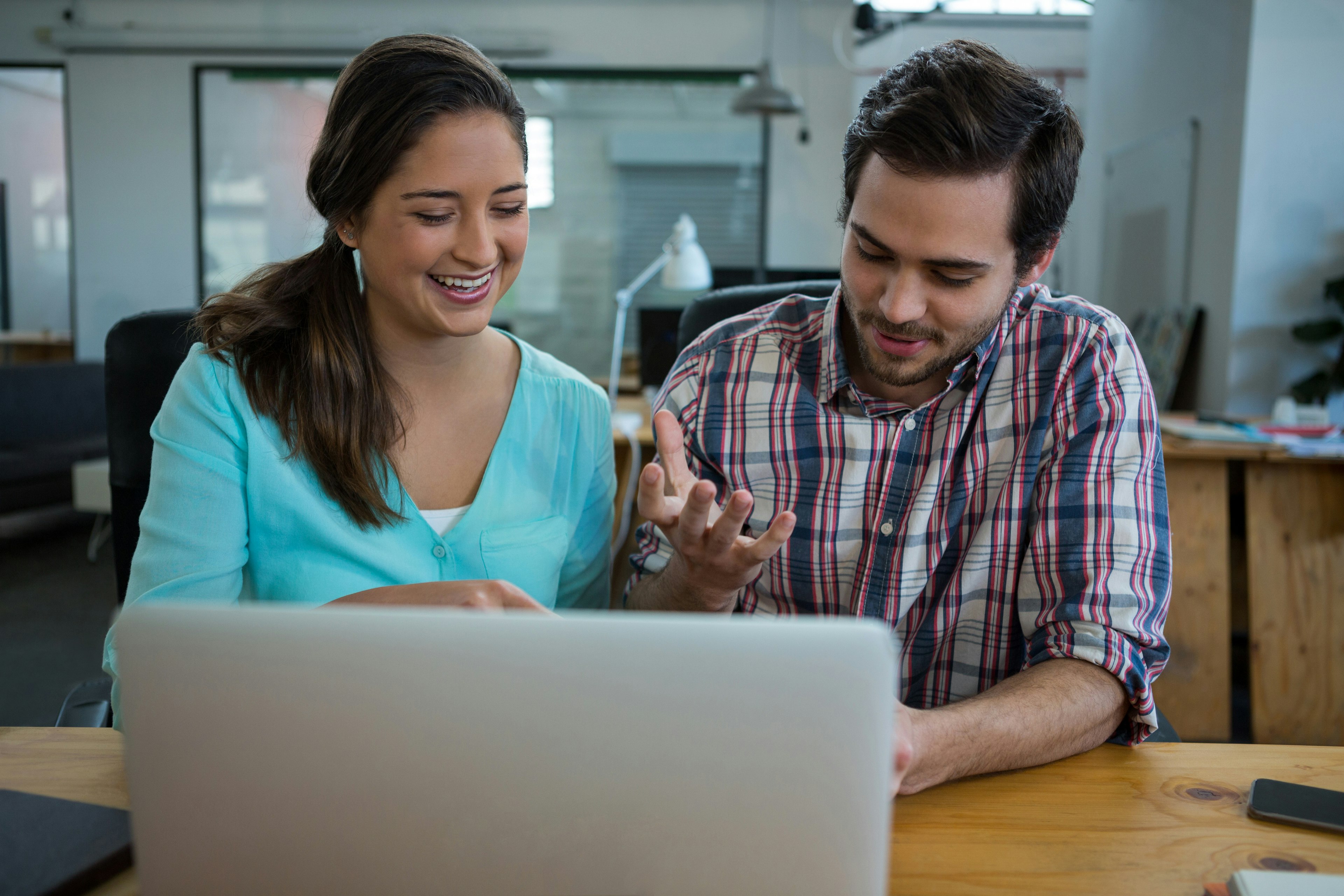 Tjej och kille sitter vid ett skrivbord framför en dator